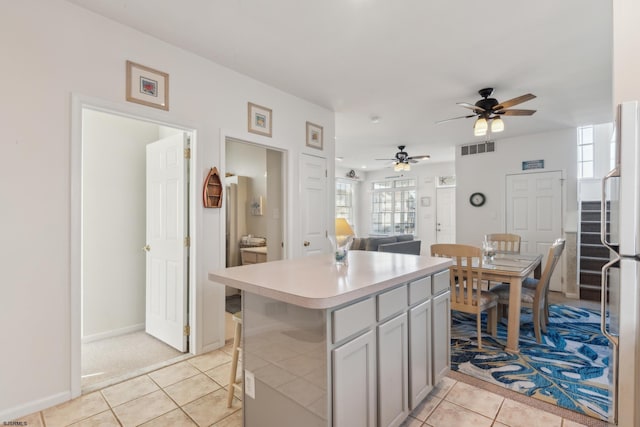 kitchen with refrigerator, a center island, light tile patterned floors, gray cabinets, and ceiling fan