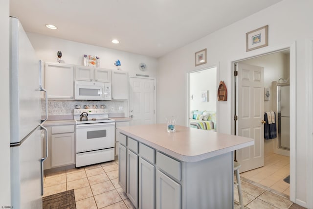 kitchen with light tile patterned floors, white appliances, decorative backsplash, and a kitchen island