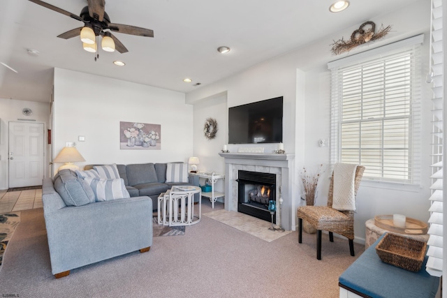 carpeted living room with ceiling fan and a fireplace