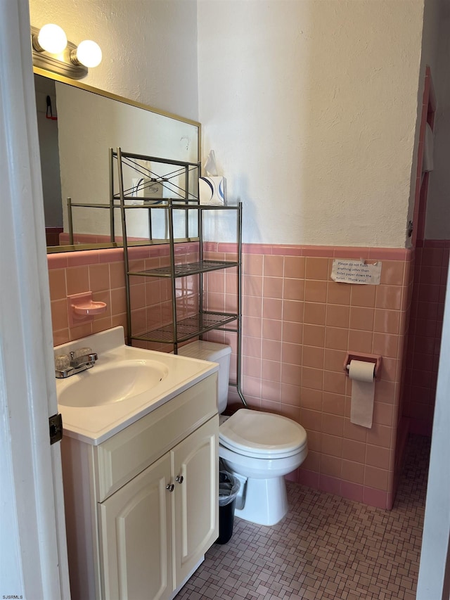 bathroom featuring tile patterned flooring, vanity, tile walls, and toilet