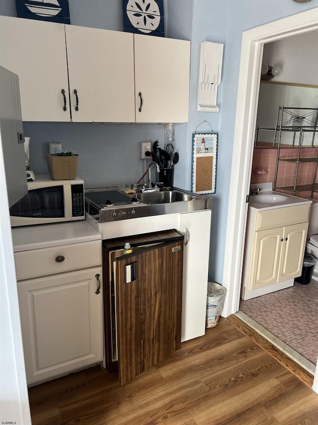 kitchen with sink, hardwood / wood-style floors, and white cabinets