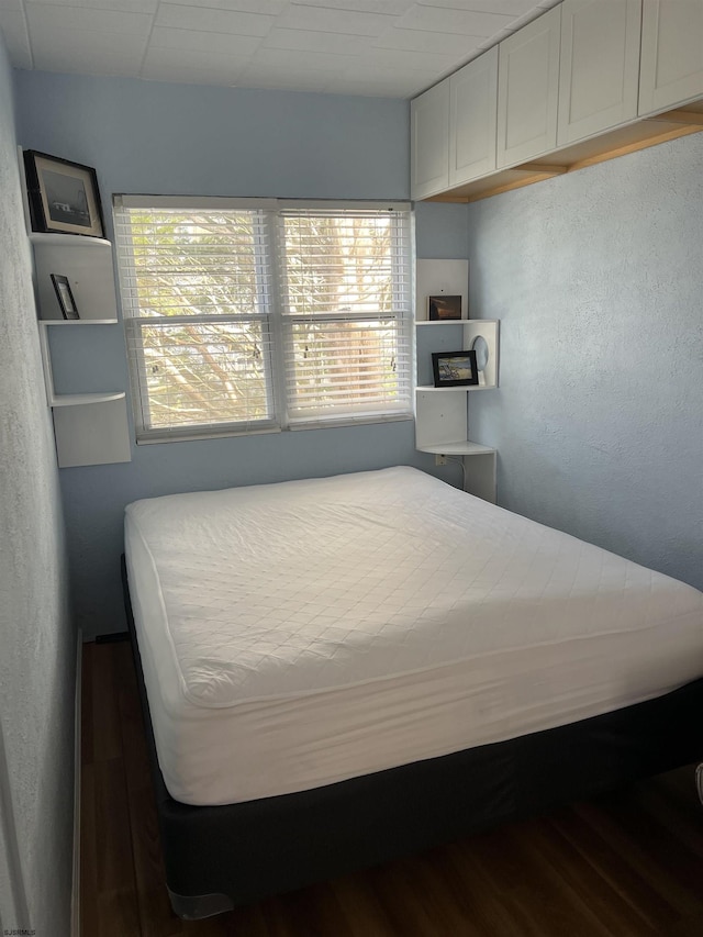 bedroom featuring multiple windows and dark hardwood / wood-style flooring