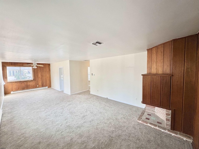 unfurnished living room featuring a baseboard radiator, light carpet, ceiling fan, and wood walls