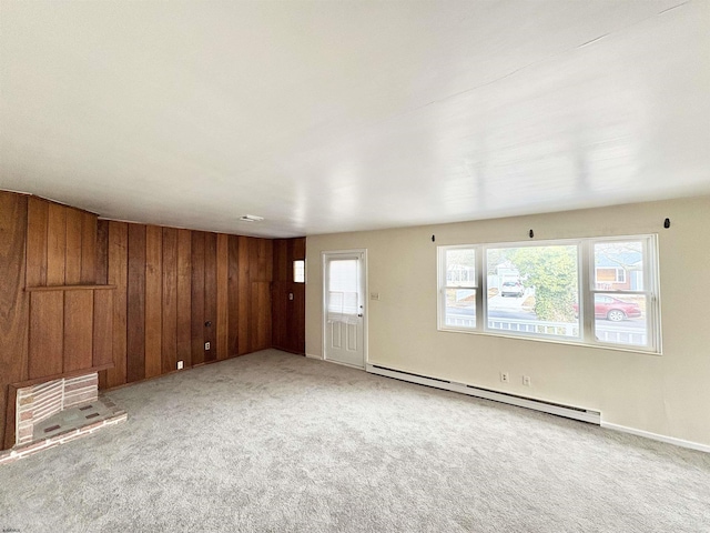 unfurnished living room featuring light carpet, a baseboard heating unit, and wooden walls