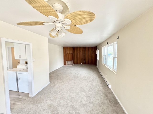 spare room with light carpet, washer and clothes dryer, a baseboard radiator, and ceiling fan