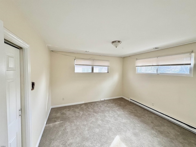 carpeted empty room featuring a baseboard heating unit and a healthy amount of sunlight