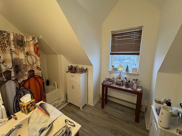 bedroom with lofted ceiling, dark hardwood / wood-style floors, and a baseboard heating unit