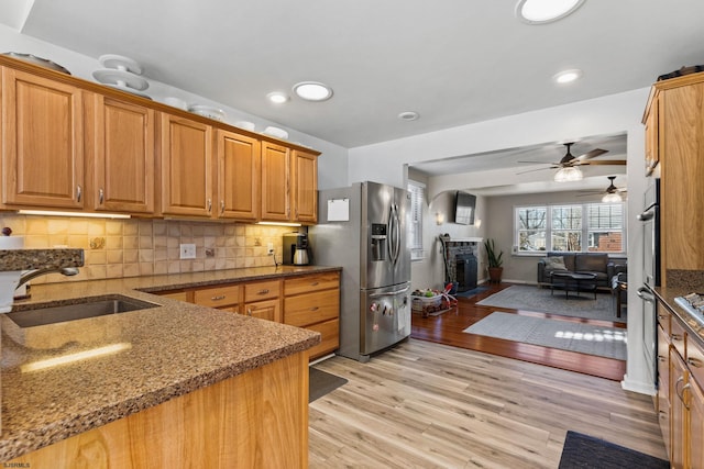 kitchen with tasteful backsplash, sink, dark stone counters, and stainless steel refrigerator with ice dispenser