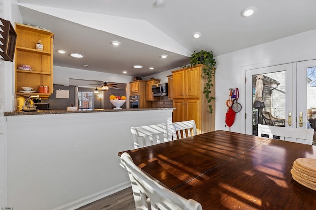 dining space with dark wood-type flooring, ceiling fan, and vaulted ceiling