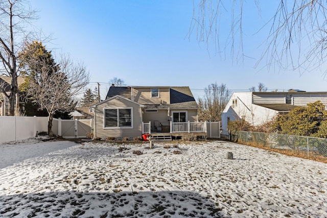 snow covered back of property with a deck