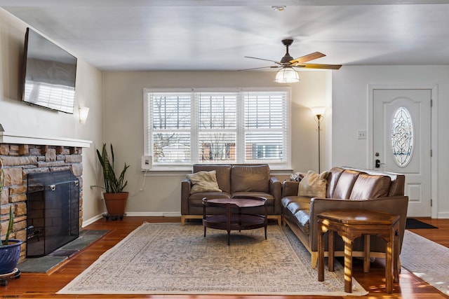 living room featuring dark wood-type flooring, ceiling fan, and a fireplace