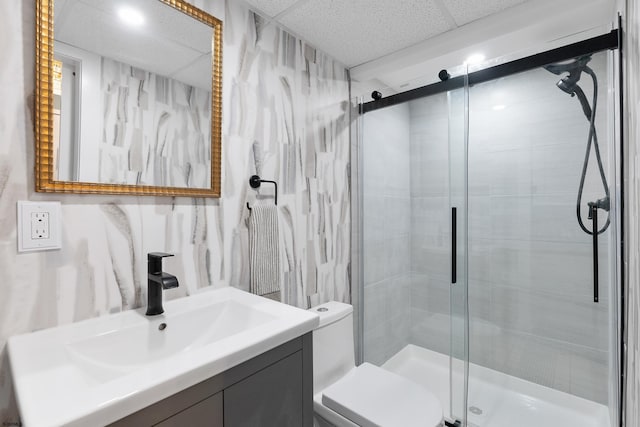 bathroom with walk in shower, vanity, toilet, and a drop ceiling