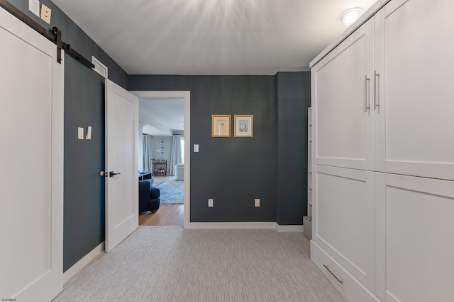 hall featuring light carpet and a barn door