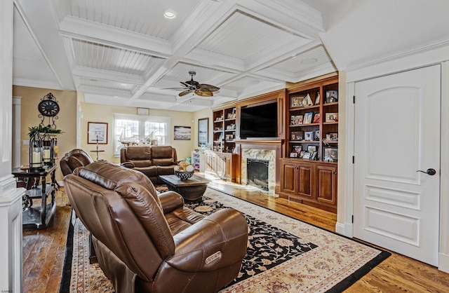 living room with hardwood / wood-style floors, coffered ceiling, ceiling fan, a high end fireplace, and beam ceiling