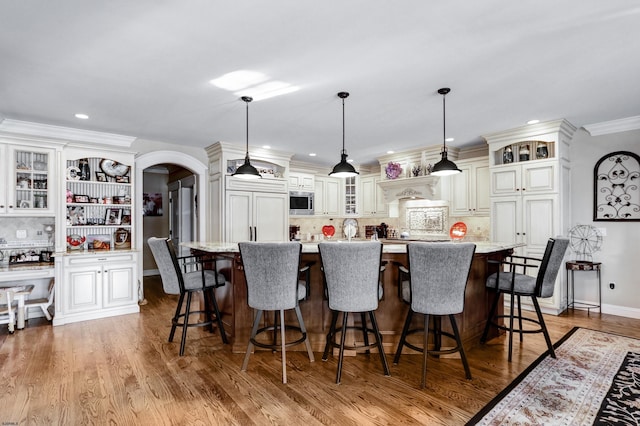 kitchen with hanging light fixtures, a kitchen island, a breakfast bar, and built in appliances