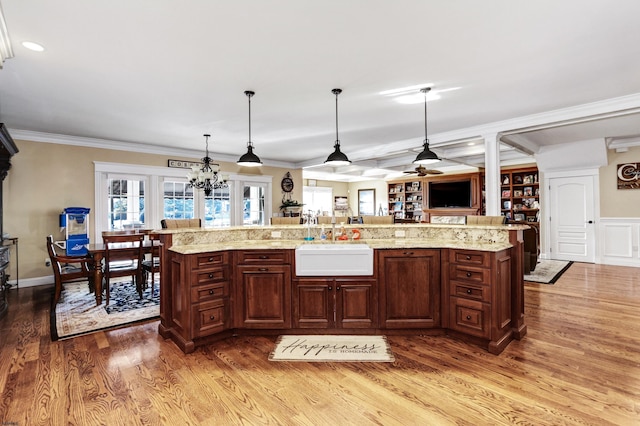 kitchen with decorative light fixtures, sink, hardwood / wood-style flooring, crown molding, and a spacious island