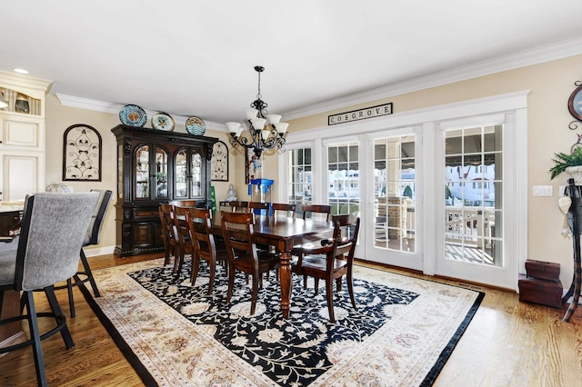 dining area with an inviting chandelier, hardwood / wood-style floors, and ornamental molding