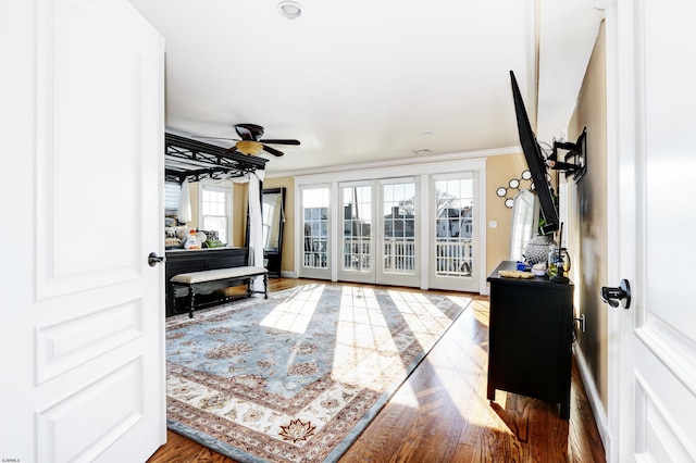 interior space with wood-type flooring, ornamental molding, and ceiling fan