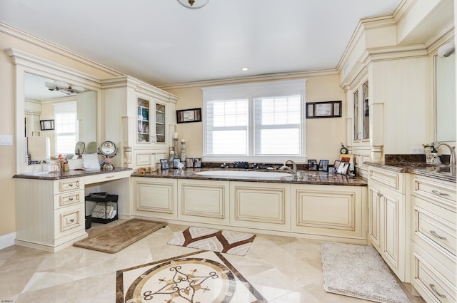 kitchen featuring dark stone countertops, cream cabinets, and plenty of natural light