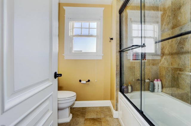 bathroom featuring combined bath / shower with glass door and toilet