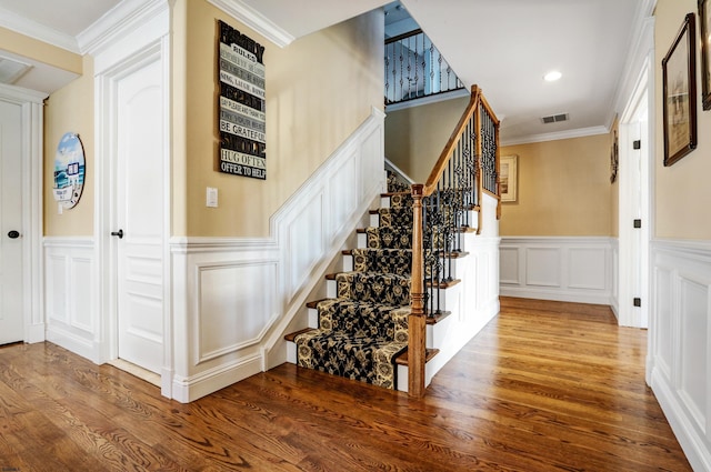 stairs with hardwood / wood-style flooring and crown molding