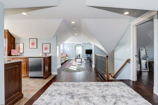 interior space featuring wood-type flooring, fridge, and vaulted ceiling