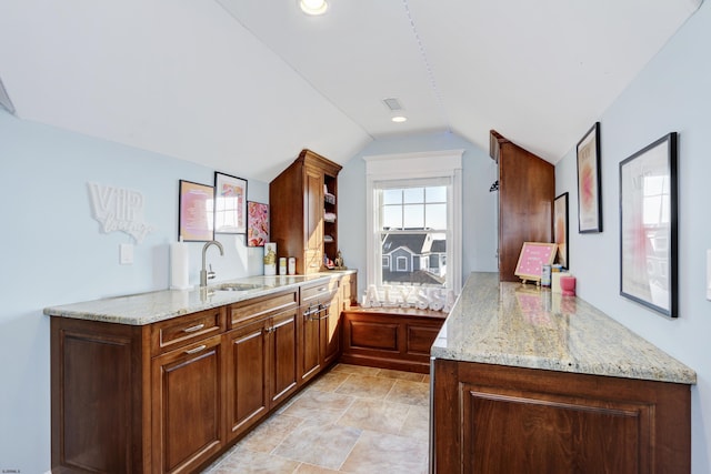 kitchen featuring sink, vaulted ceiling, light stone countertops, and kitchen peninsula