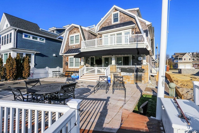 rear view of property with a balcony, covered porch, and a patio