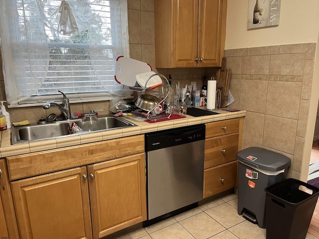 kitchen with sink, tile walls, stainless steel dishwasher, tile counters, and light tile patterned floors