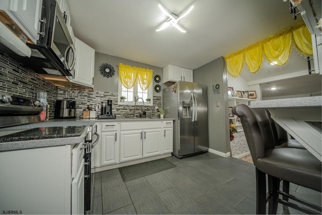 kitchen featuring white cabinetry, appliances with stainless steel finishes, sink, and backsplash