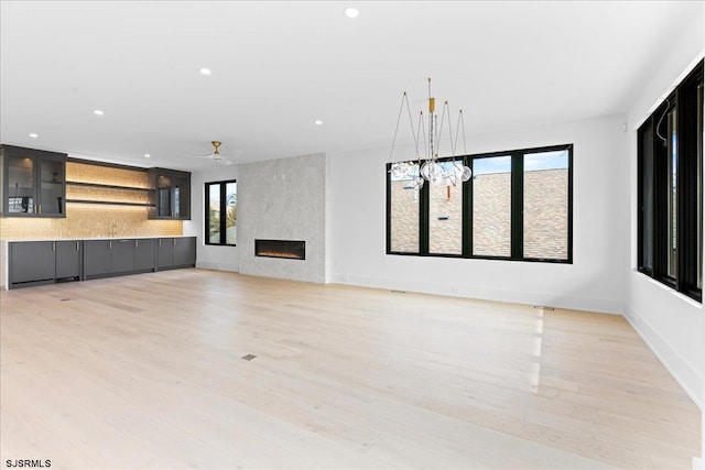 unfurnished living room featuring light hardwood / wood-style flooring, a large fireplace, and ceiling fan