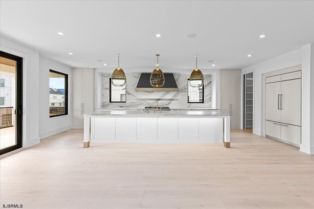 kitchen with decorative light fixtures, light hardwood / wood-style floors, exhaust hood, and a spacious island