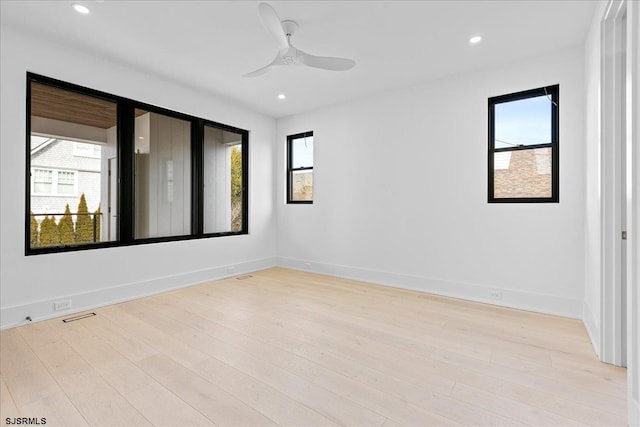 empty room featuring plenty of natural light, ceiling fan, and light wood-type flooring