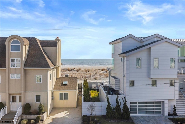 exterior space with a garage, a water view, and a view of the beach