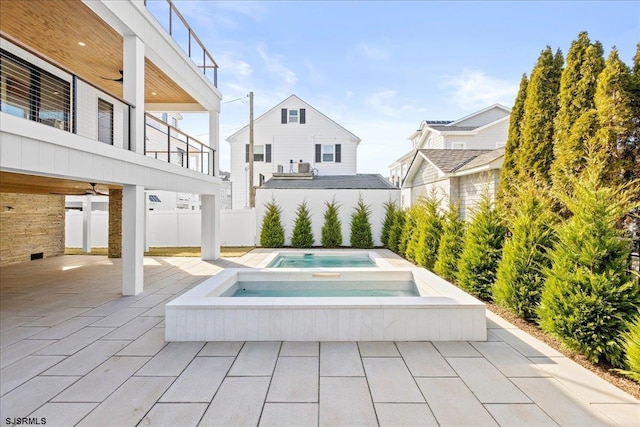 view of patio with an in ground hot tub and a balcony