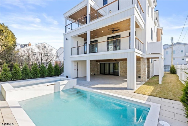 back of house with ceiling fan, a balcony, a patio area, and a lawn