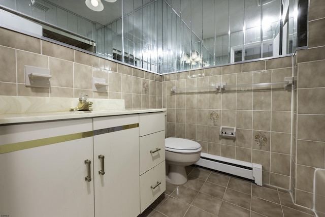 bathroom with tile walls, a baseboard heating unit, vanity, tile patterned floors, and toilet