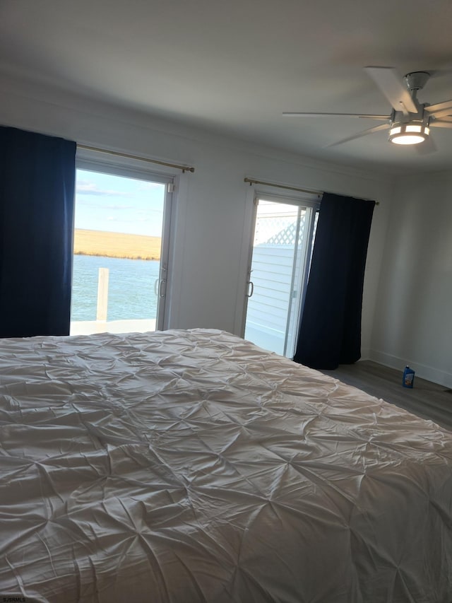 bedroom featuring a water view, ceiling fan, access to exterior, and hardwood / wood-style flooring