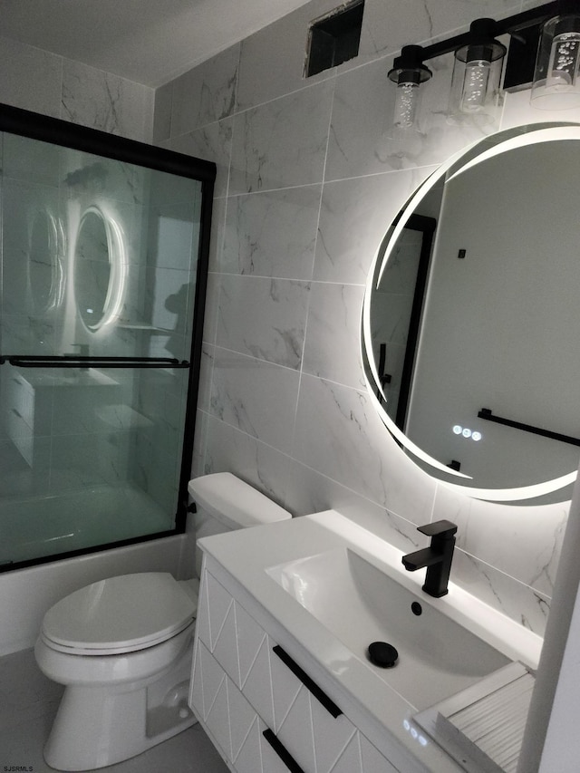 full bathroom with tile walls, backsplash, shower / bath combination with glass door, vanity, and toilet