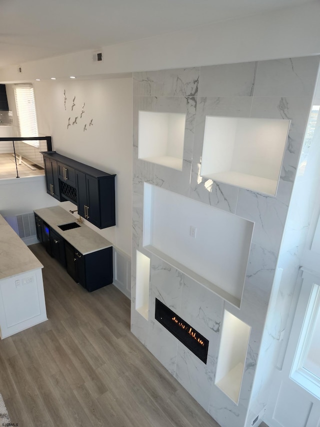 living room with sink, light hardwood / wood-style flooring, and a premium fireplace