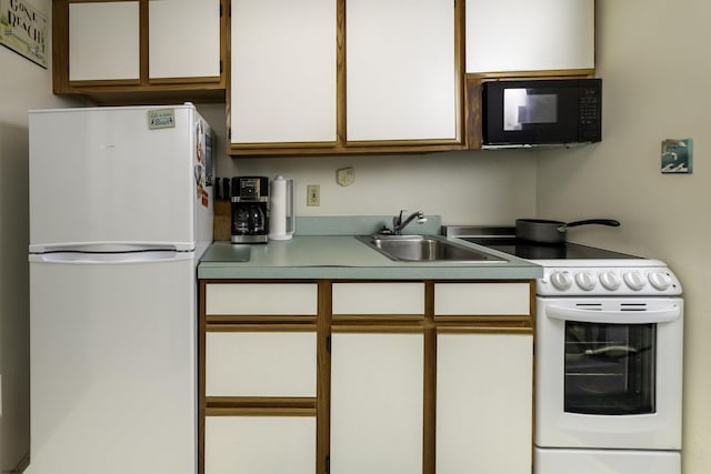 kitchen featuring white cabinetry, white appliances, and sink