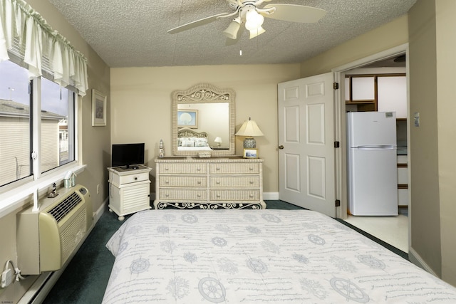 bedroom with a textured ceiling, an AC wall unit, white fridge, ceiling fan, and carpet