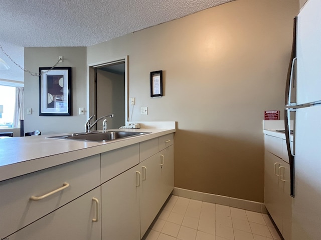 kitchen with sink, fridge, and a textured ceiling