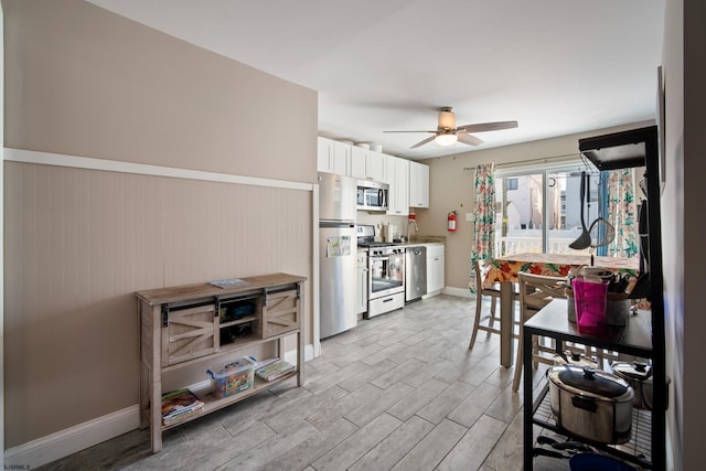 kitchen featuring white cabinetry, sink, ceiling fan, stainless steel appliances, and light wood-type flooring