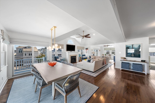 dining area with ceiling fan with notable chandelier, vaulted ceiling, and dark hardwood / wood-style floors