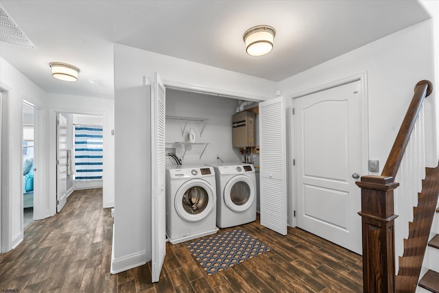 laundry area with water heater, washing machine and dryer, and dark hardwood / wood-style flooring