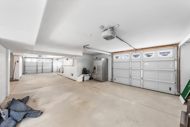 garage with a garage door opener and stainless steel refrigerator with ice dispenser