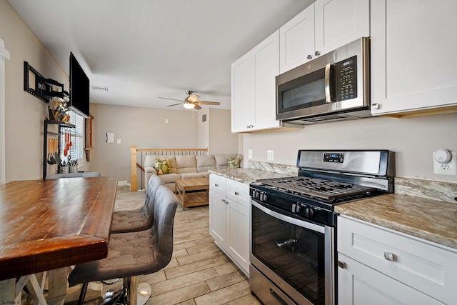 kitchen featuring white cabinetry, light stone countertops, stainless steel appliances, and ceiling fan