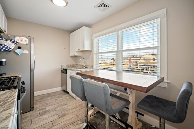 kitchen featuring white cabinetry, sink, light wood-type flooring, and appliances with stainless steel finishes