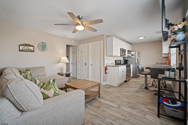 living room with ceiling fan and light hardwood / wood-style flooring